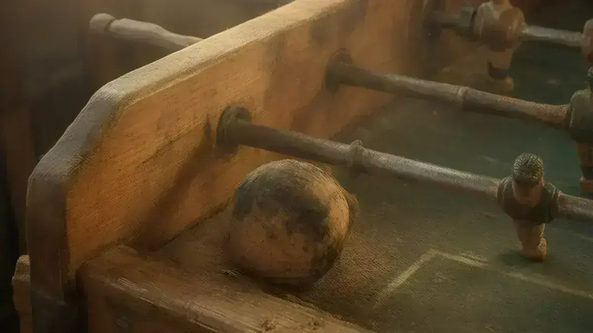 Mesa de futbolín antigua de madera de pino con las barras cromadas y una bola de corcho sobre el campo