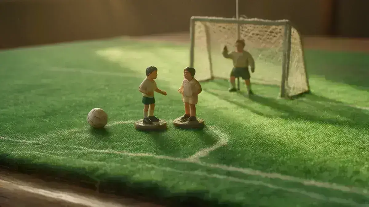 Subbuteo figures on the green baize with the ball in front of the shooting line and the goalkeeper on his rod